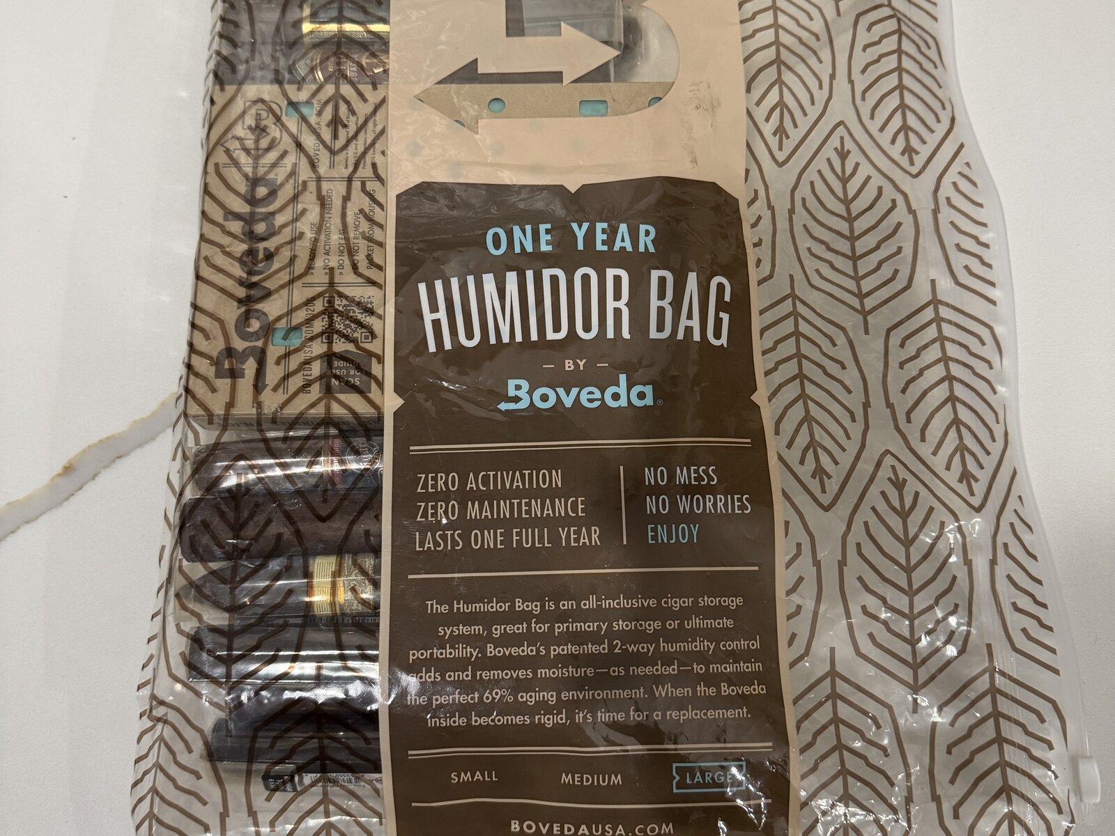 Boveda One Year Humidor Bag laid flat, clear resealable bag with a brown leaf pattern and a label reading One Year Humidor Bag by Boveda, size Large selected