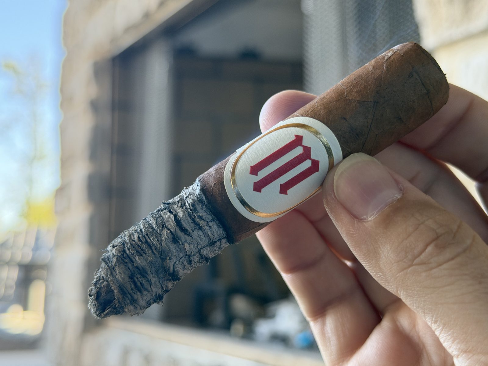Crowned Heads Mil Días Sublime two thirds of the way through the second third, band still on, with a long dark gray ash