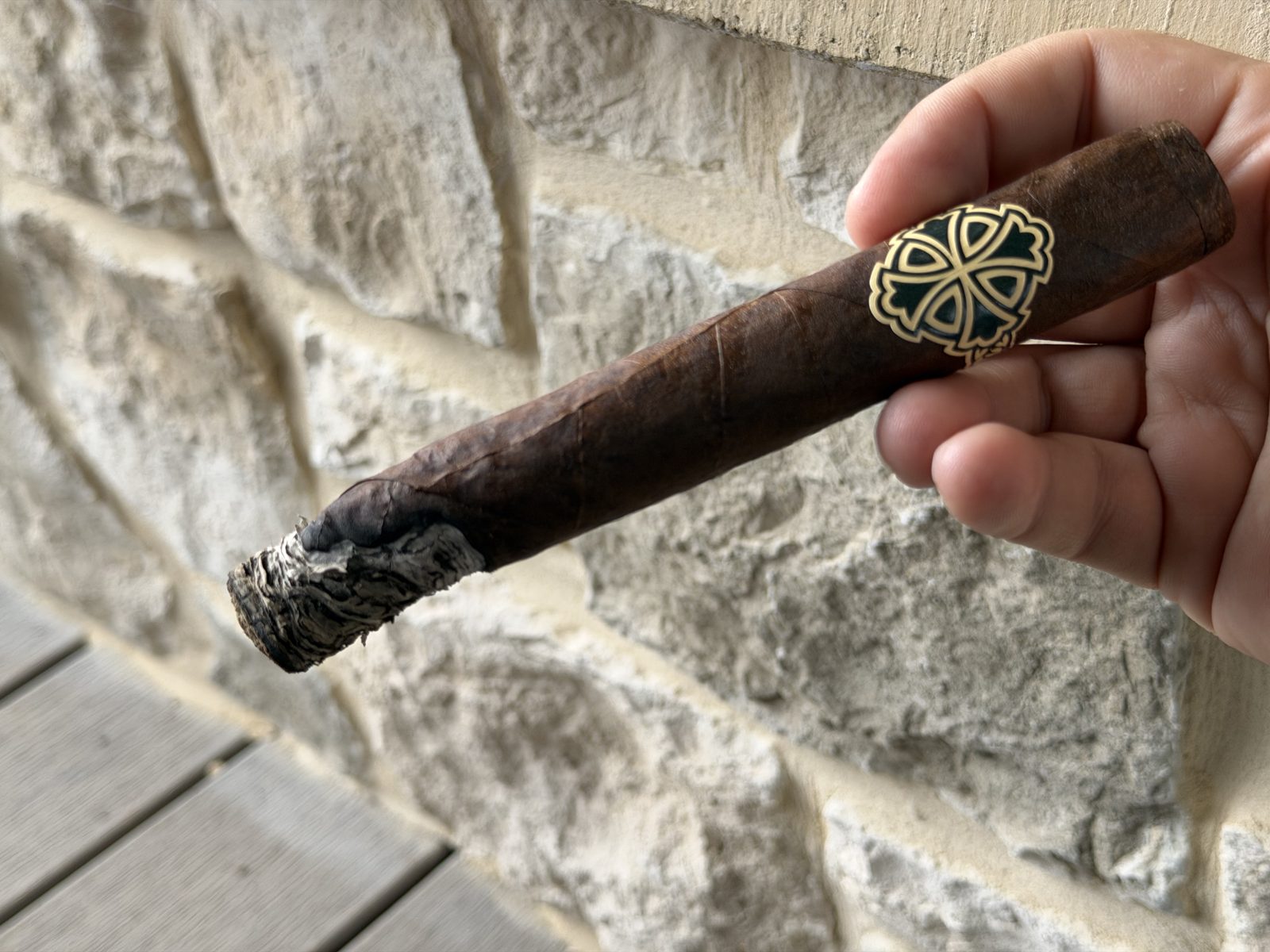 Dunbarton Sin Compromiso Seleccion No. 7 held in hand with the band still on, the foot showing one side burned well ahead of the rest