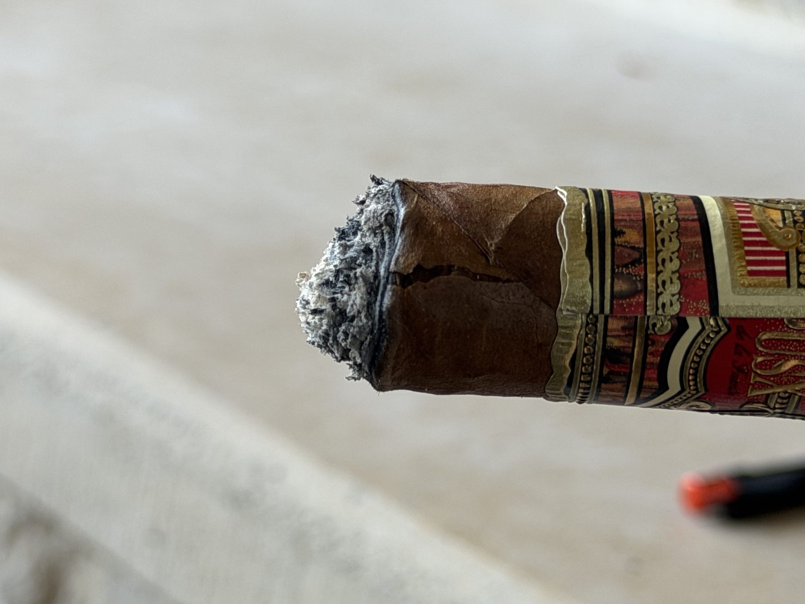 Foot of the Fuente Fuente Opus X Perfecxion X after the full ash fell, showing the off-center ligero core and the crack running toward the band