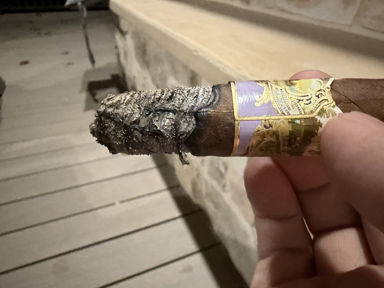 La Aroma de Cuba Noblesse Viceroy near the end of the second third, band still on, with a crooked, uneven gray ash and a wavy burn line