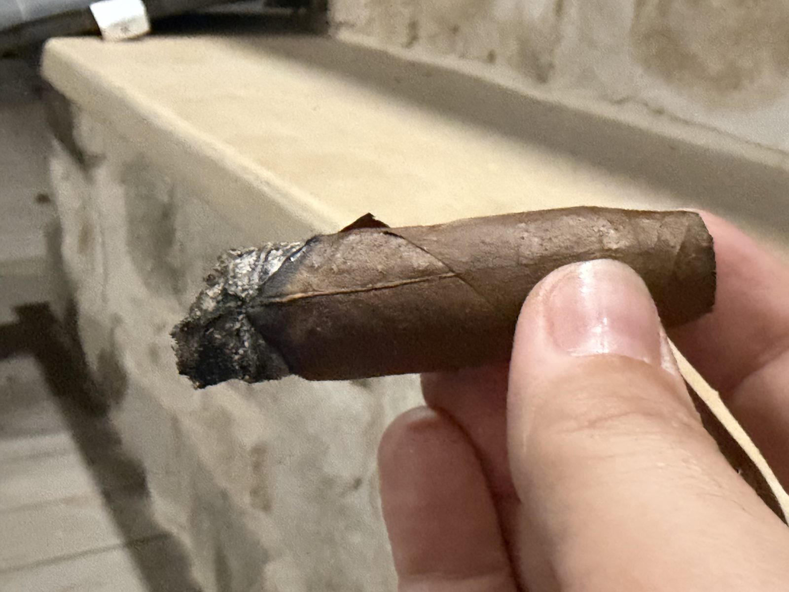 The La Aroma de Cuba Noblesse Viceroy where I set it down, held between two fingers, a short way into the final third with the wrapper crack still ahead of the burn line
