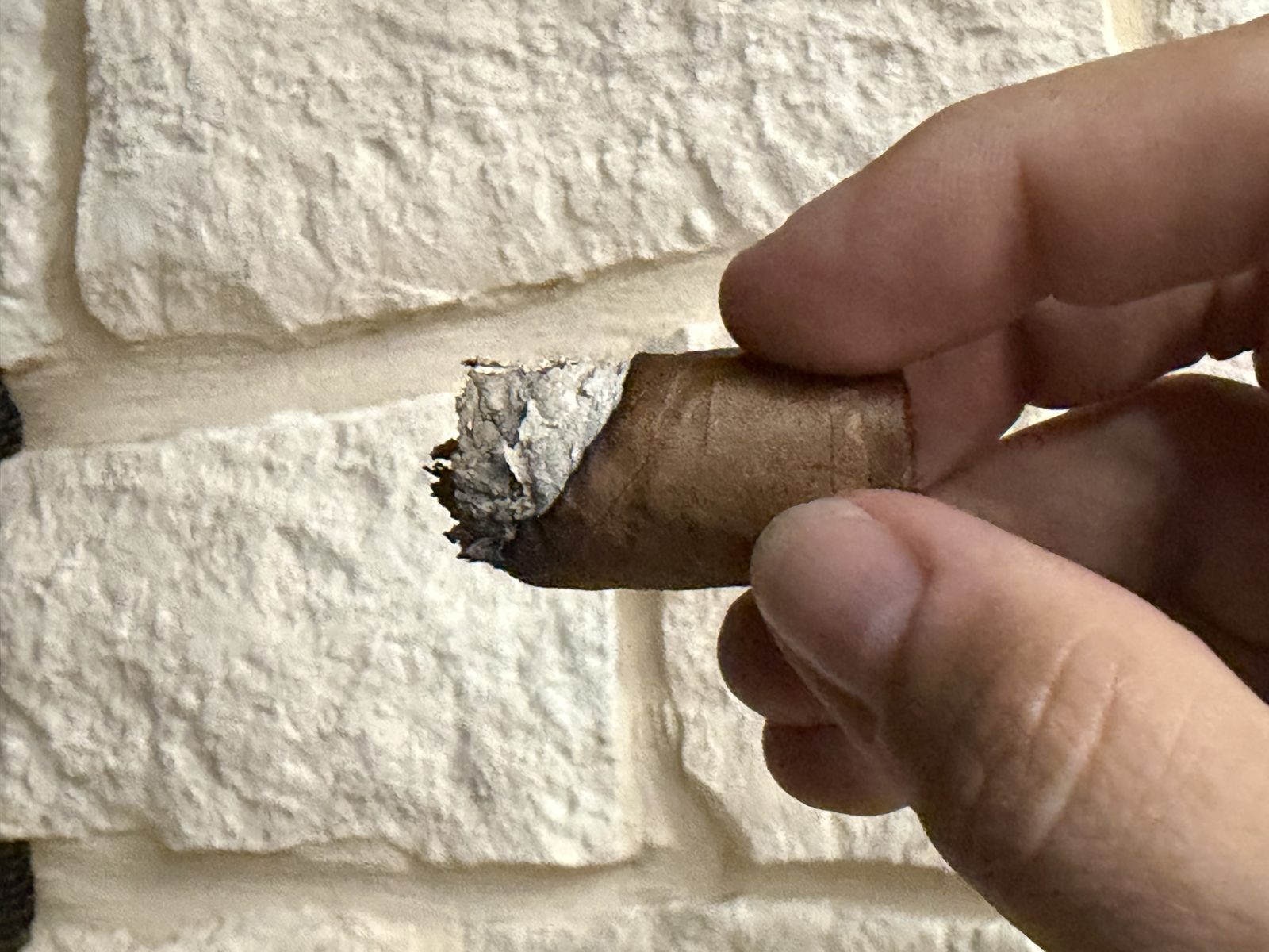 My Father Blue Toro nub held between fingers, short with a wavy burn line