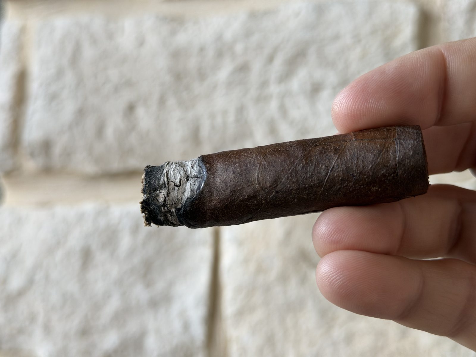 Oliva Serie V Maduro Toro a quarter inch into the final third, short ash on the foot and no bands, held in fingertips against a stone wall right before being laid down