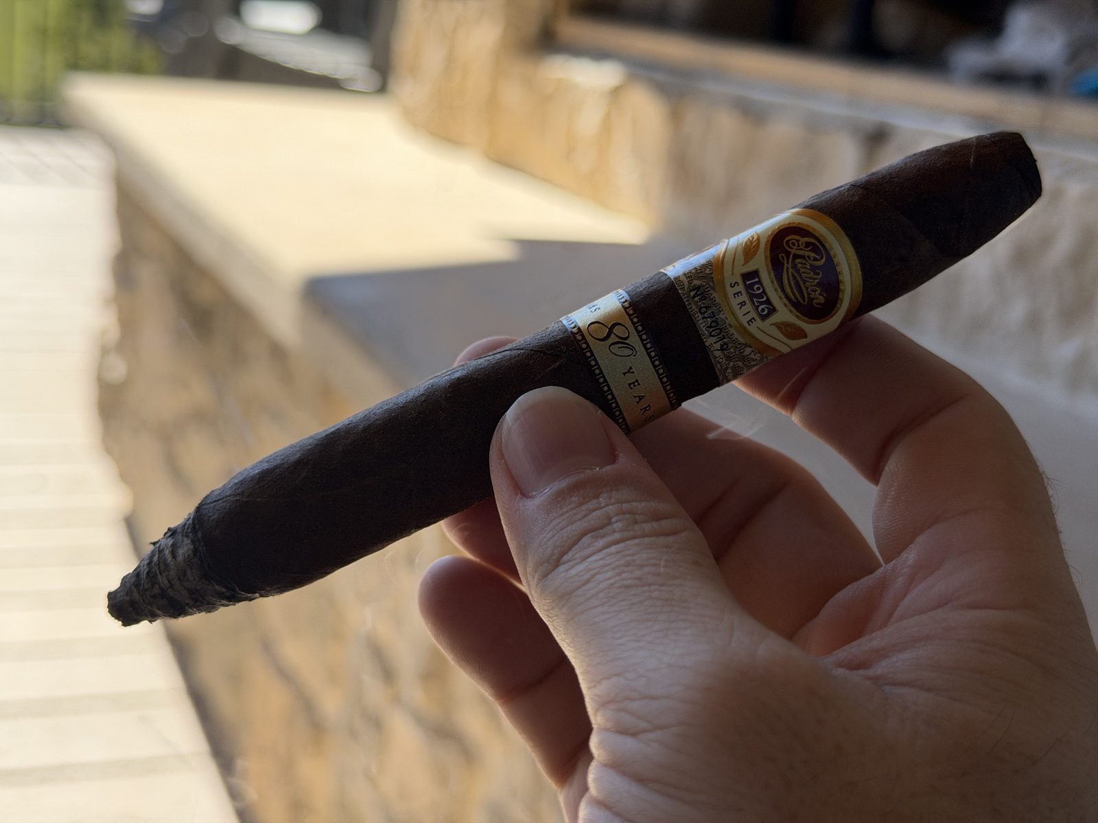 Padrón 1926 Serie 80 Years Maduro lit and burning through the tapered perfecto tip on the back deck