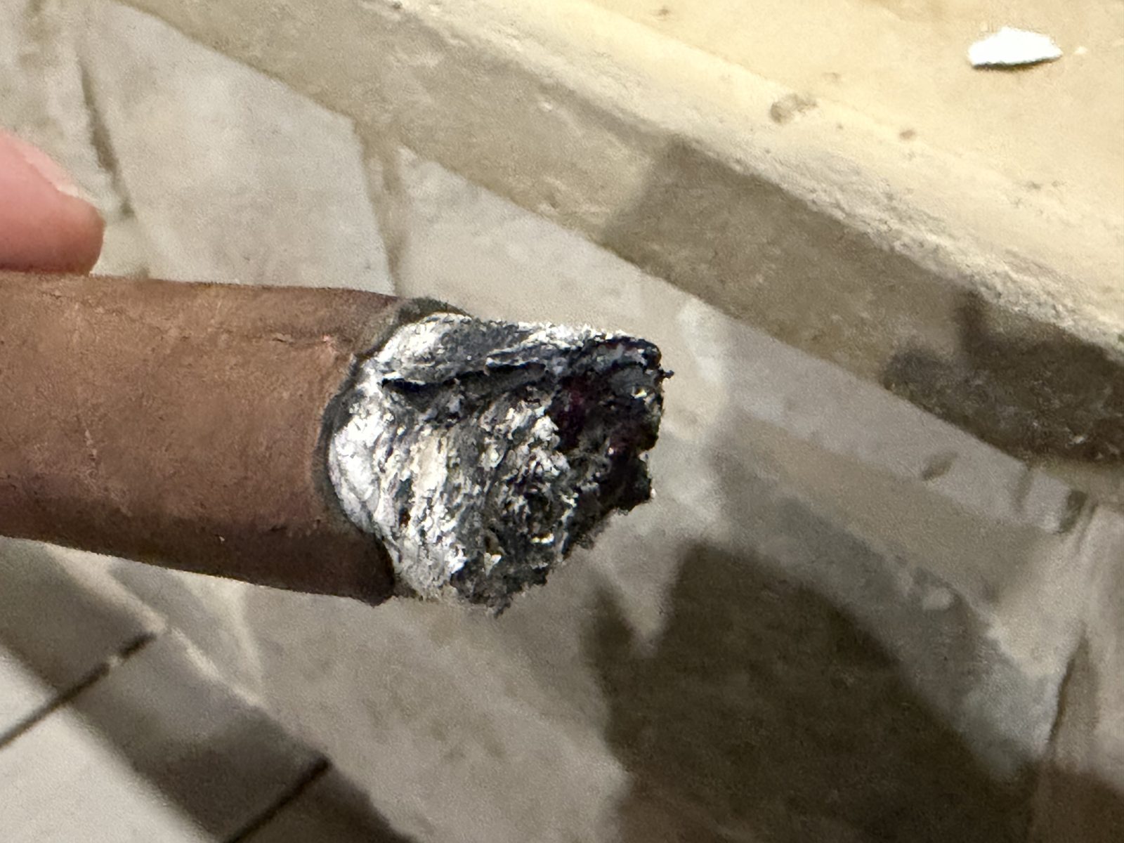 Foot of the Perdomo 30th Anniversary Maduro Epicure just after ashing in the second third, charred and uneven with a dark gap visible in the tobacco under the wrapper