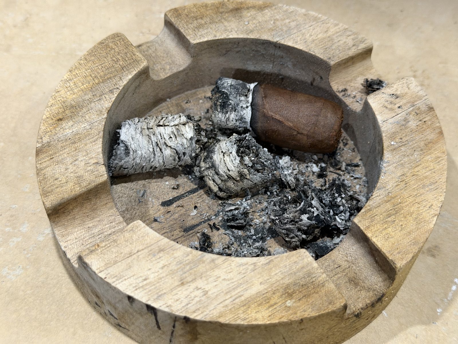 The butt of the Perdomo 30th Anniversary Maduro Epicure in a wooden ashtray surrounded by chunks of gray ash, about half an inch of smokable cigar left