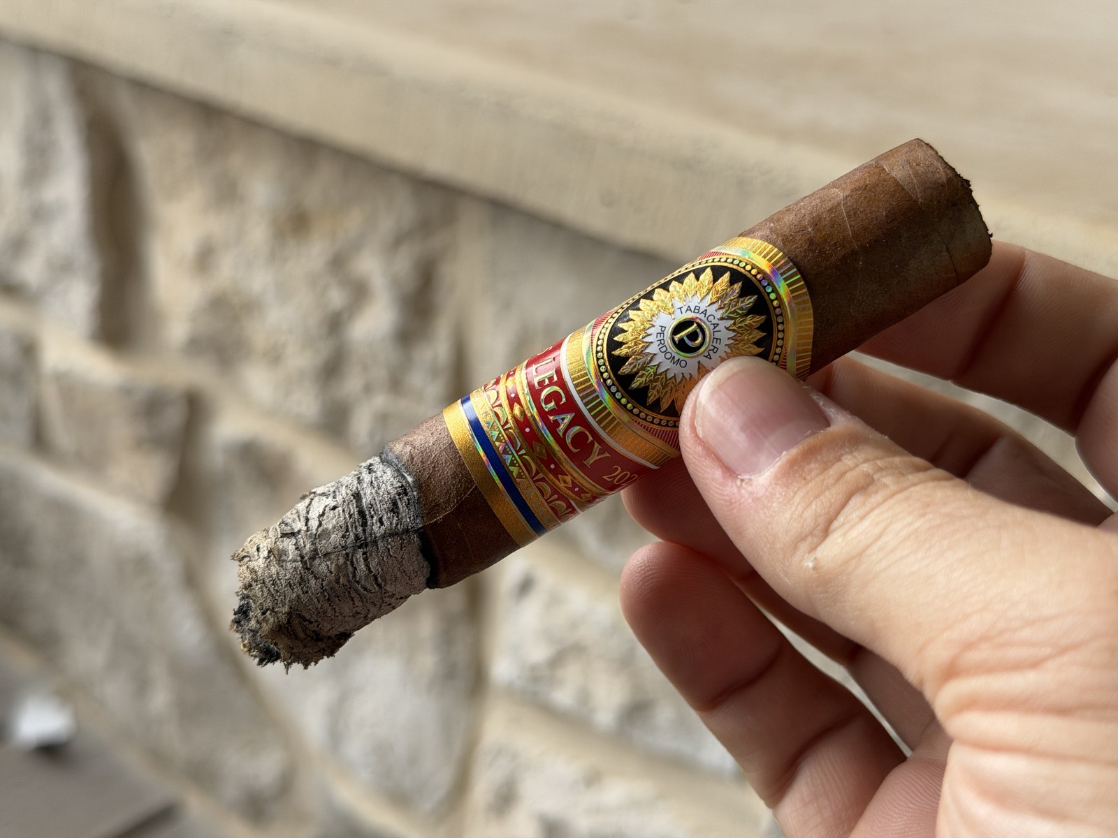 Perdomo Legacy Nicaraguan Shade-Grown Epicure mid-smoke with a thick gray ash stack, band still on